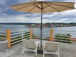 a table with two chairs and an umbrella next to the water at APARTHOTEL VISTA LAGO in Flores