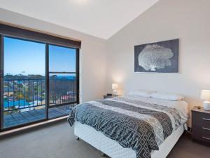 
a bedroom with a large bed and a large window at Sheridan Court on Wagonga in Narooma
