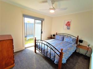 ein Schlafzimmer mit einem Bett mit blauer Decke und einem Fenster in der Unterkunft My Abode in Albury in Albury