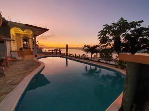 a swimming pool with a view of the ocean at sunset at APARTHOTEL VISTA LAGO in Flores