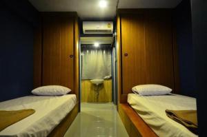 a bedroom with two beds and a bathroom with a window at HOOT Hostel & Ratchada in Bangkok