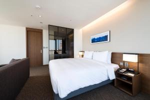 Pokój hotelowy z dużym łóżkiem i telewizorem w obiekcie Ramada Encore by Wyndham Busan Haeundae w Pusanie