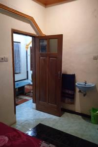 uma casa de banho com uma porta de madeira e um lavatório em Gebby Homestay Bromo RedPartner em Pasuruan
