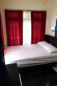 um quarto com uma cama grande e cortinas vermelhas em Gebby Homestay Bromo RedPartner em Pasuruan