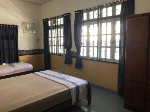 a bedroom with two beds and two windows at AbgZul Homestay in Kota Bharu