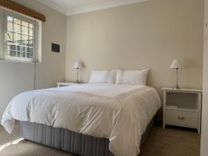 1 dormitorio blanco con 1 cama grande y 2 mesitas de noche en BaobabSuites, en Johannesburgo