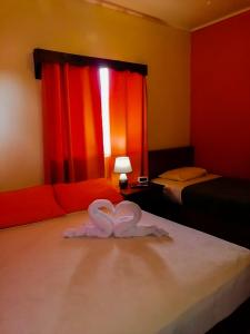 una camera con due letti con un cuore bianco sul letto di Boquete Town Hostal a Boquete