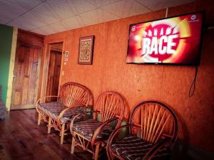 a room with four chairs and a television on the wall at Boquete Town Hostal in Boquete