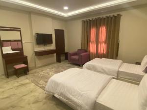 una camera d'albergo con due letti e un pianoforte di شقق القارات السبع الاحساء a Al Hofuf