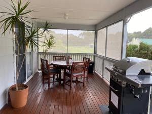 a balcony with a table and chairs and a grill at Lazy Days Cottage - Victor Harbor in Hindmarsh Valley