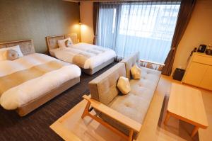 a hotel room with two beds and a couch at Rinn Horikawa Gojo in Kyoto