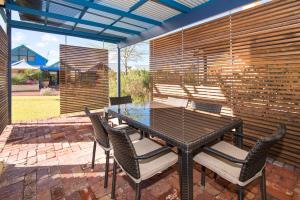 a patio with a table and chairs and a fence at Dunsborough Beach Cottages in Dunsborough