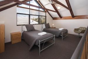 a attic room with two beds and a window at Dunsborough Beach Cottages in Dunsborough