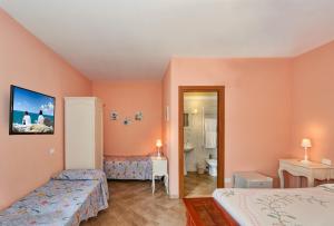 a hotel room with two beds and a bathroom at La Papaya in Marina di Pisa