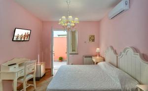 um quarto com paredes cor-de-rosa, uma cama e uma secretária. em La Papaya em Marina di Pisa