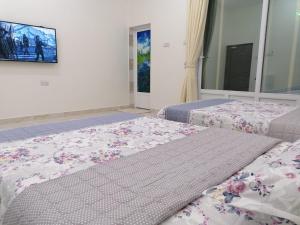 a bedroom with two beds and a tv on the wall at Misfah View in Misfāh