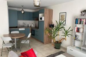 une cuisine avec des armoires bleues, une table et des chaises dans l'établissement Cocon sur cour, à Thonon-les-Bains