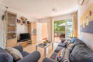 Una sala de estar con un sofá azul y un televisor. en Casa Hygge, en Calas de Mallorca