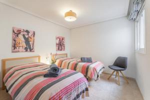 Un dormitorio con dos camas y una silla dentro. en Casa Hygge, en Calas de Mallorca 17 fotos más