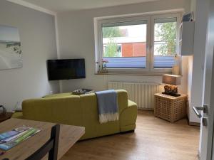 ein Wohnzimmer mit einem grünen Sofa und einem TV in der Unterkunft Ferienwohnungen Felix und Jan in Horumersiel
