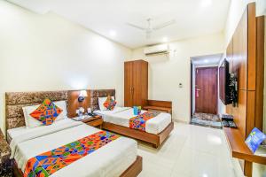 a hotel room with two beds and a television at FabHotel Prime President- Bhopal Railway Station in Bhopal +23 photos
