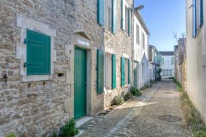 サント・マリー・ド・レにあるMACÉDOCY Maison de charme au cœur du Villageの古石造りの建物の緑の襖の通り