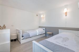 ein weißes Schlafzimmer mit einem Bett und einem Bettrock in der Unterkunft MACÉDOCY Maison de charme au cœur du Village in Sainte-Marie-de-Ré