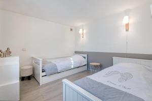 a white bedroom with a bed and a bedskirts at MACÉDOCY Maison de charme au cœur du Village in Sainte-Marie-de-Ré