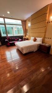 a bedroom with a large bed and wooden floors at Charming Motel in Hualien City
