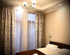 1 dormitorio con 1 cama y una ventana con cortinas en Atlant Hotel en Úzhgorod