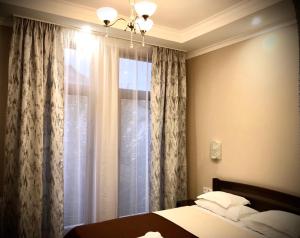 a bedroom with a bed and a window with curtains at Atlant Hotel in Uzhhorod