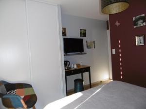 Schlafzimmer mit einem Bett, einem Schreibtisch und einem TV in der Unterkunft Maison d'Hôtes La Marie Pierre in Pluherlin