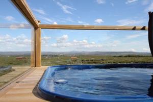 a hot tub on a deck with a large window at Blue View Cabin 3A With private hot tub in Reykholt