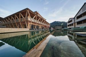 a wooden building on the water next to some buildings at HUBERTUS Mountain Refugio Allgäu in Balderschwang