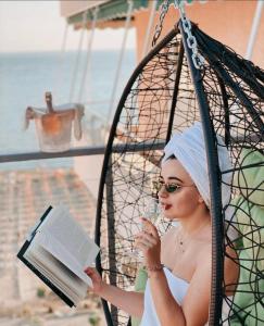 a woman sitting in a swing reading a book at Gjilani Premium Hotel in Shëngjin +76 photos