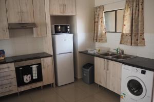 una pequeña cocina con nevera y fregadero en OR Tambo Self Catering Apartments, The Willows en Boksburg