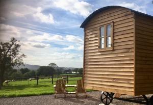 a tiny house with two chairs and a window at Shepherd’s Hut - The Mule in Newent