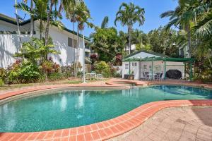 a swimming pool in front of a house at Costa Royale Beachfront Apartment in Trinity Beach