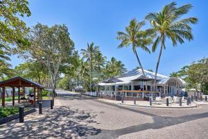 a park with palm trees and a building at Costa Royale Beachfront Apartment in Trinity Beach +7 photos