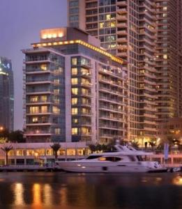 a boat in the water in front of a large building at Nuran Marina in Dubai