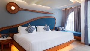 a bedroom with a white bed and a blue wall at The Oceanic Sportel Phuket - SHA Extra Plus in Phuket Town