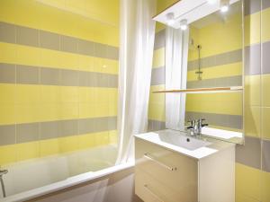 a yellow and gray bathroom with a sink and a tub at Vacancéole - Résidence L'Edelweiss in Les Deux Alpes