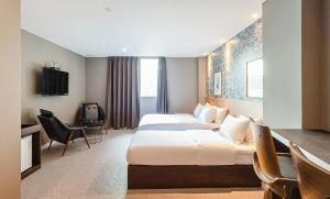 a hotel room with two beds and a desk at No. 25 Signature Hotel Daecheong in Busan