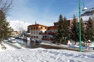 una calle nevada con edificios y coches aparcados en la carretera en Vacancéole - Résidence L'Edelweiss, en Les Deux Alpes