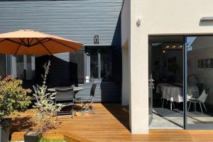 a patio with an umbrella and a table and chairs at La Baie Latitude, gîte proche mer avec jardin in Le Crotoy