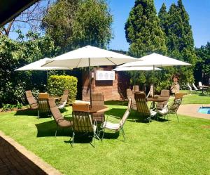 grupa stołów i krzeseł z parasolami w obiekcie Elgro Hotel Potchefstroom w mieście Potchefstroom