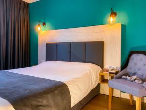 a bedroom with a large bed and a chair at Logis Clermotel - Hôtel & Restaurant in Agnetz