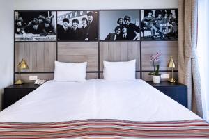 a bedroom with a large white bed with pictures on the wall at Customs House Hotel & SPA in Rostov on Don
