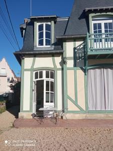 a house with a table and chairs in front of it at L'Eldorado in Courseulles-sur-Mer