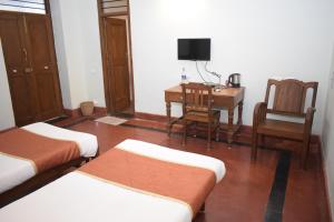 a room with two beds and a desk and a chair at Lakshmi Vilas in Mannārgudi